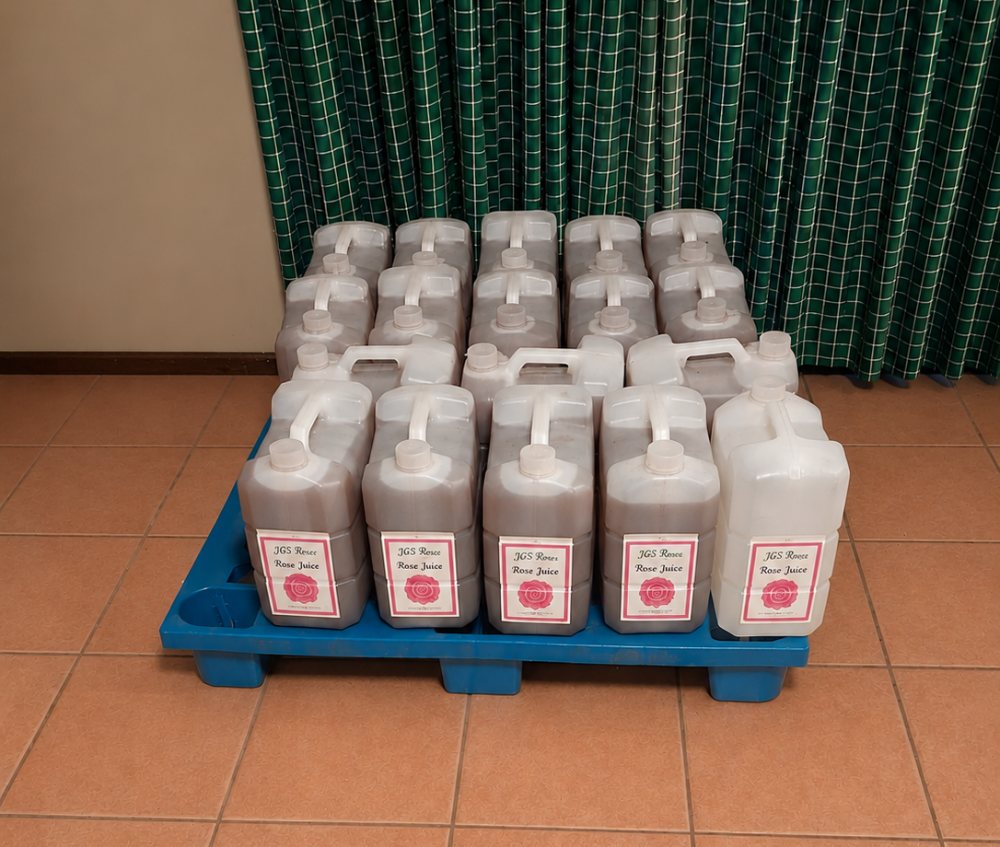 bottles of rose juice, rose feed sitting on the floor on a pallet